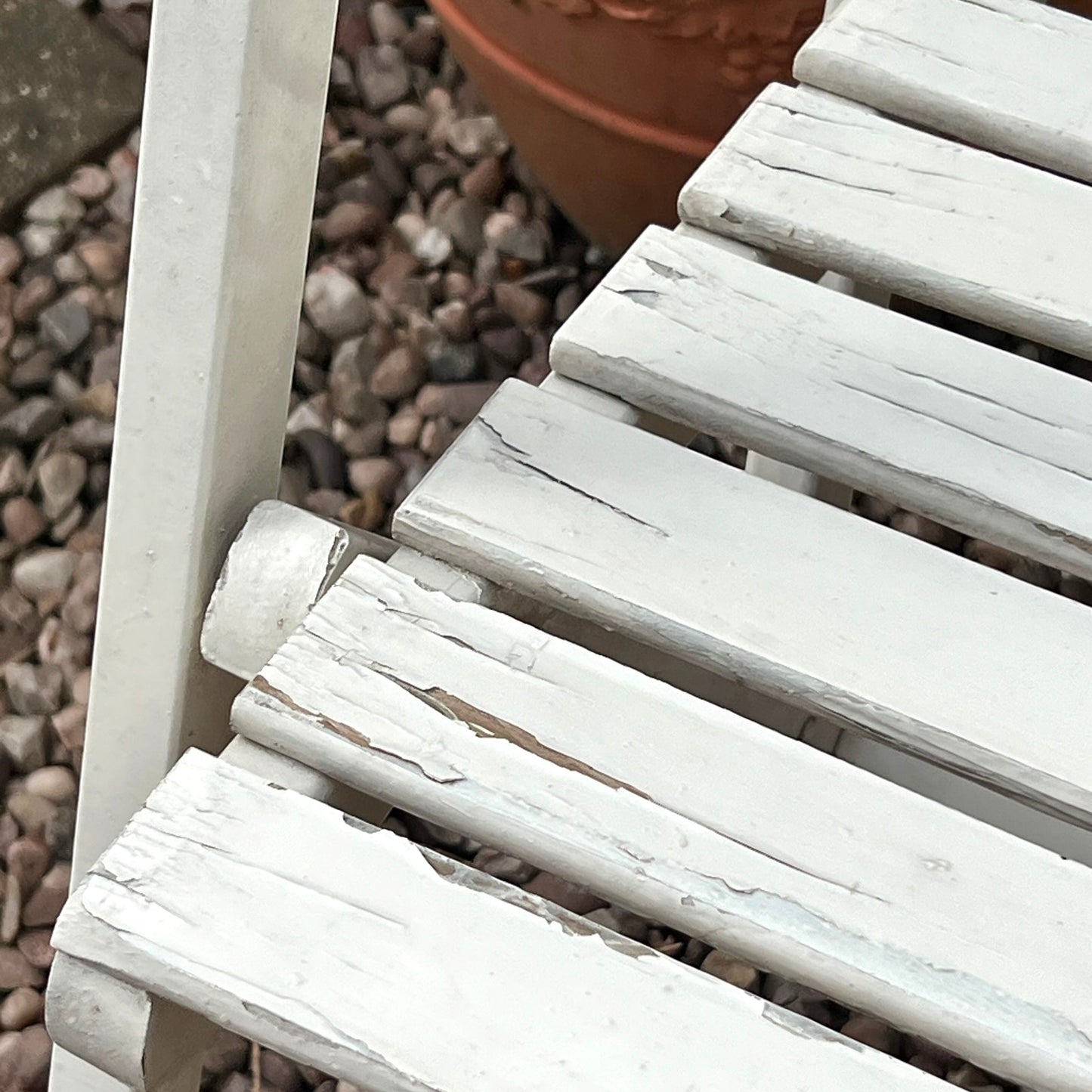 Close-up detail of French wooden slatted chairs, highlighting their condition in an outdoor setting.