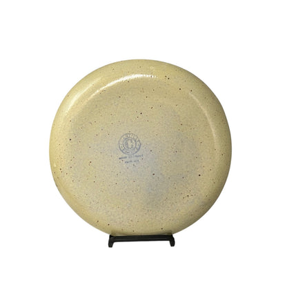 Beige plate on a stand with a visible brand logo against a white background