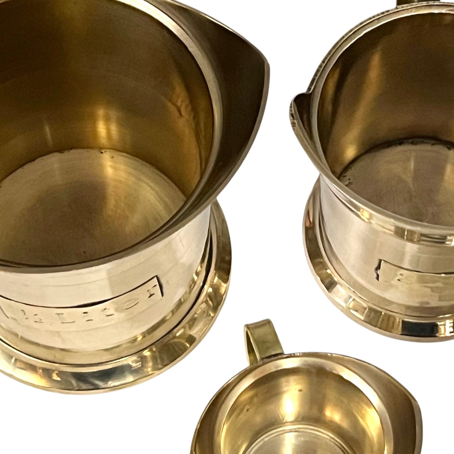 Three brass cups with handles on a white background