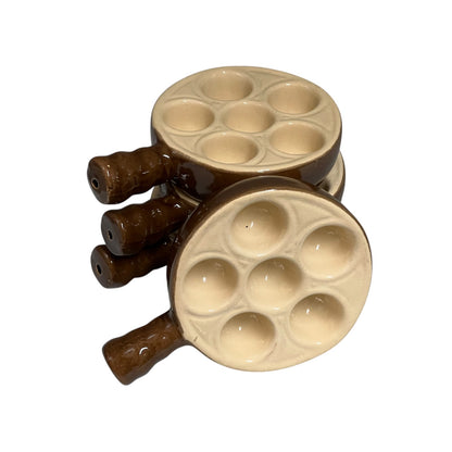 Set of four brown and beige ceramic mini snail dishes stacked together on a plain white background.