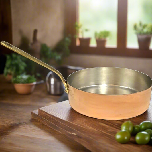 Copper frying pan on a wooden surface with a blurred kitchen background  for sale from All Things French Store