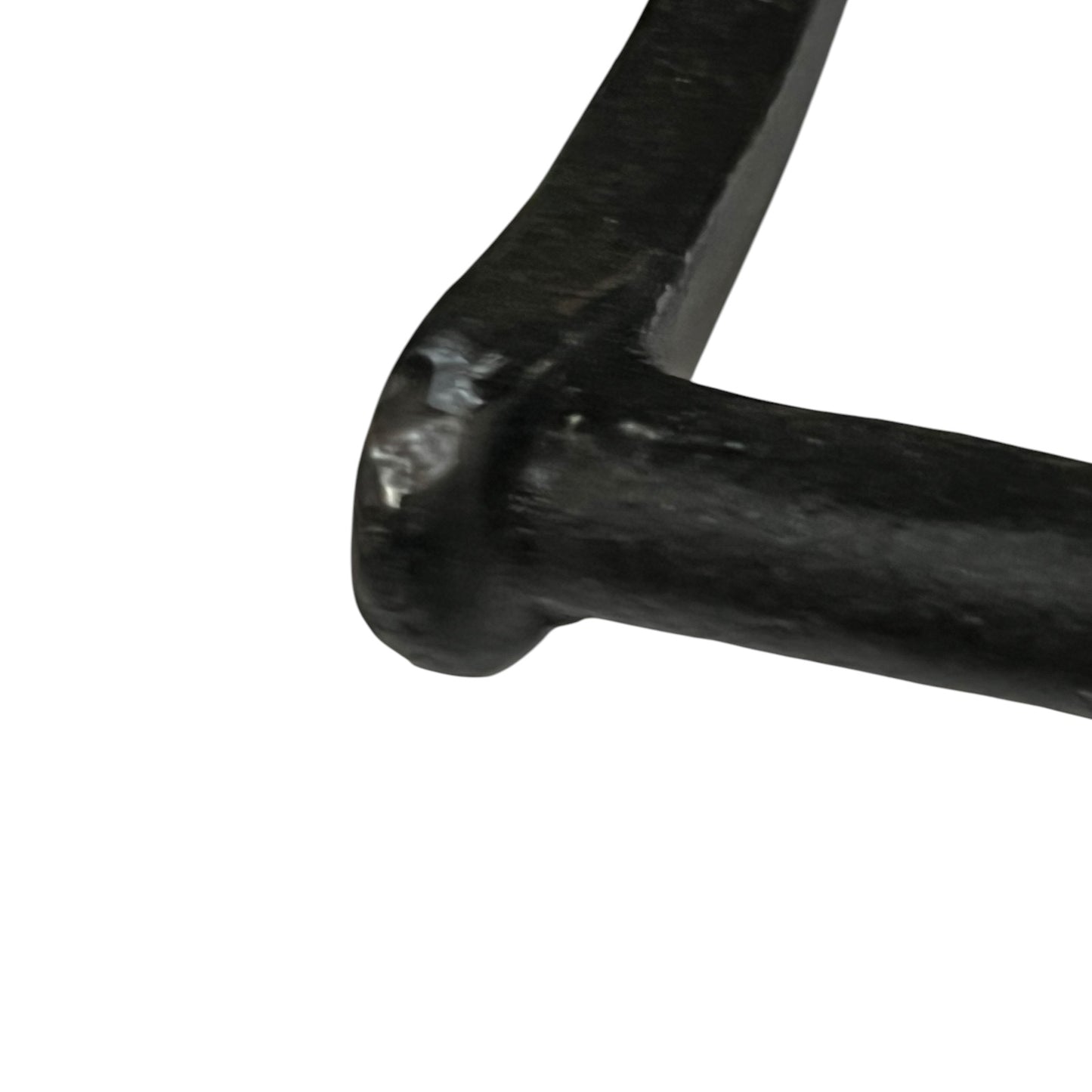 Close-up of a black cast iron or forged metal hardware piece, showing a textured, dark-finished corner joint on a plain white background.