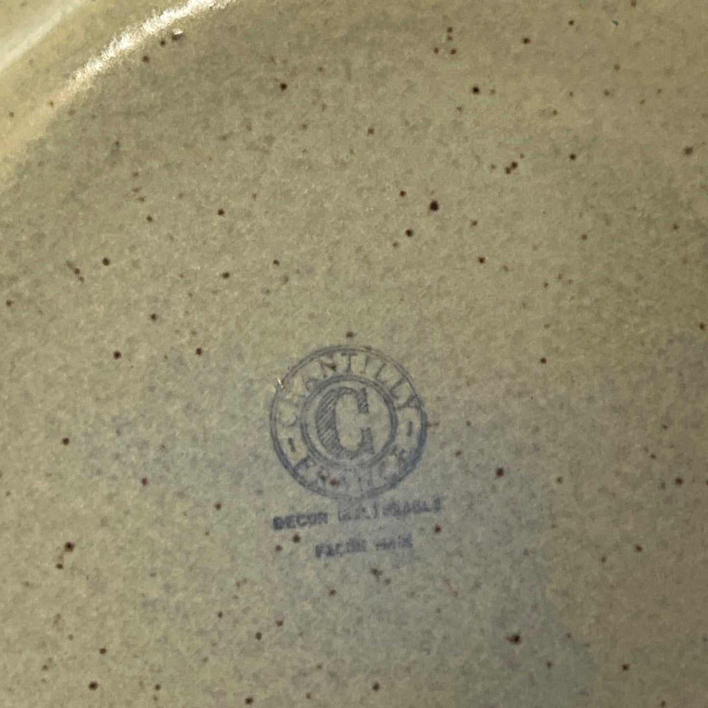 Ceramic plate with a visible brand logo on a textured beige background