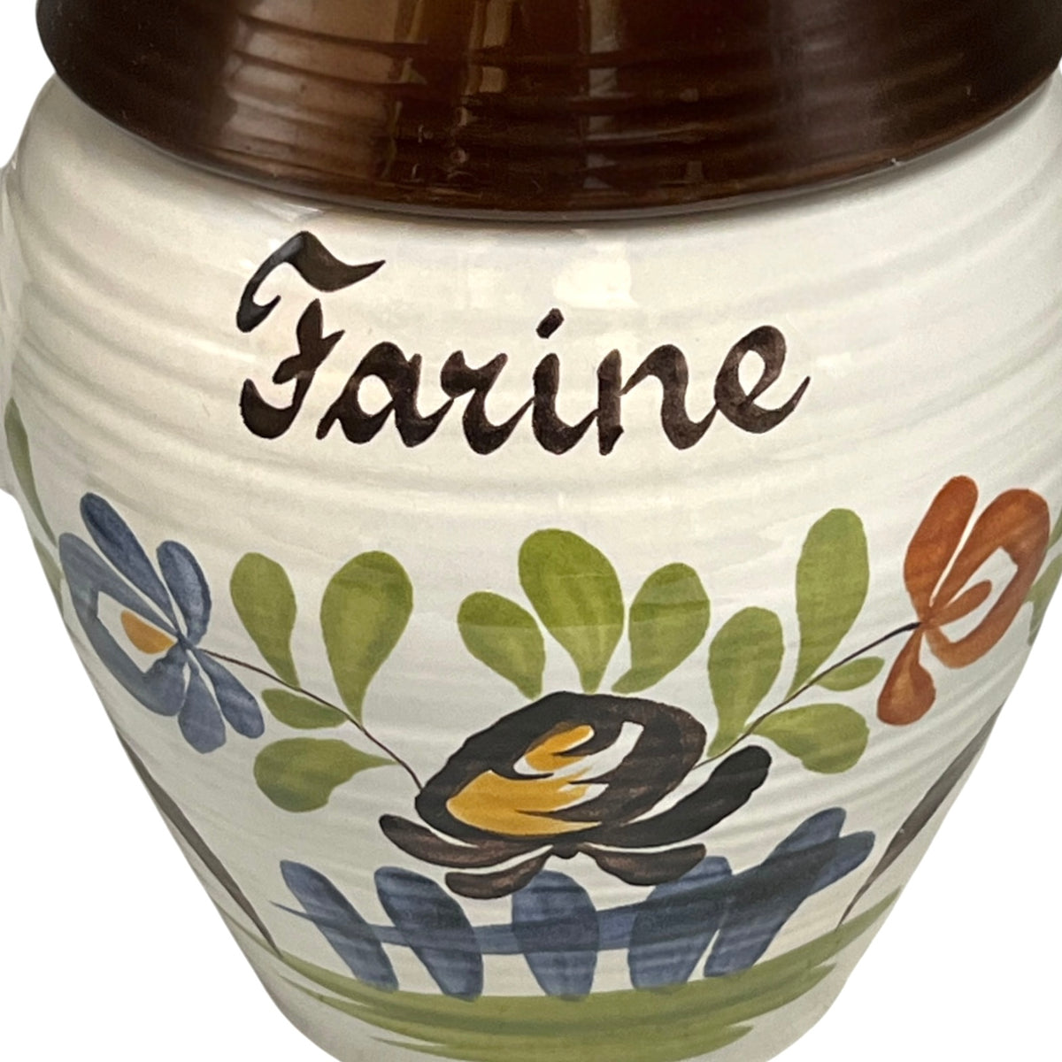 A close-up of a ceramic jar labeled 'Farine' with a dark brown lid, decorated with a hand-painted floral pattern in green, blue, orange, and black on an off-white body.