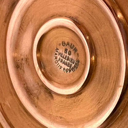 Close-up of a bronze or copper object with 'GAUR' branding and text.