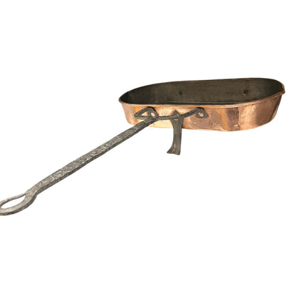 Antique French copper roasting pan with a long handle on a white background