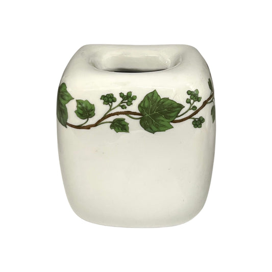 White ceramic toothbrush pot with green leaf design on a white background