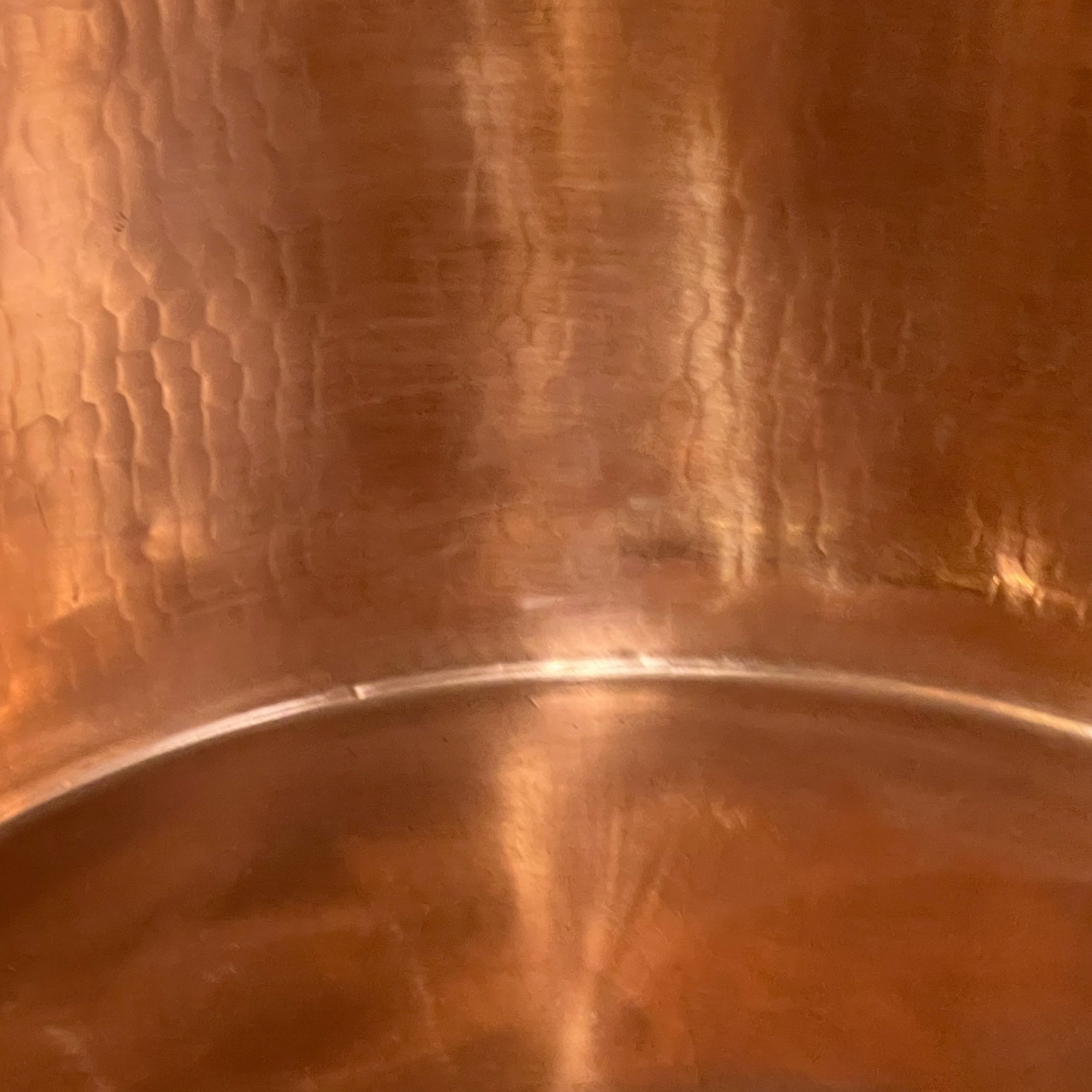 Close-up of copper sink with brass pop up waste on a white background