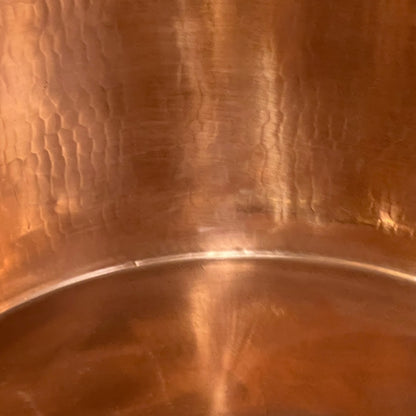 Close-up of copper sink with brass pop up waste on a white background