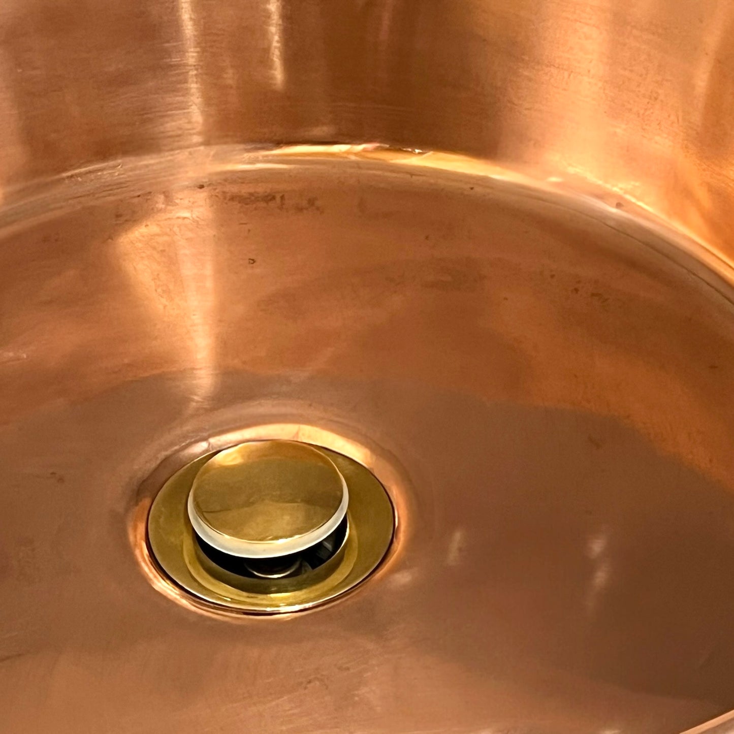 Close-up of a copper sink with a drain plug