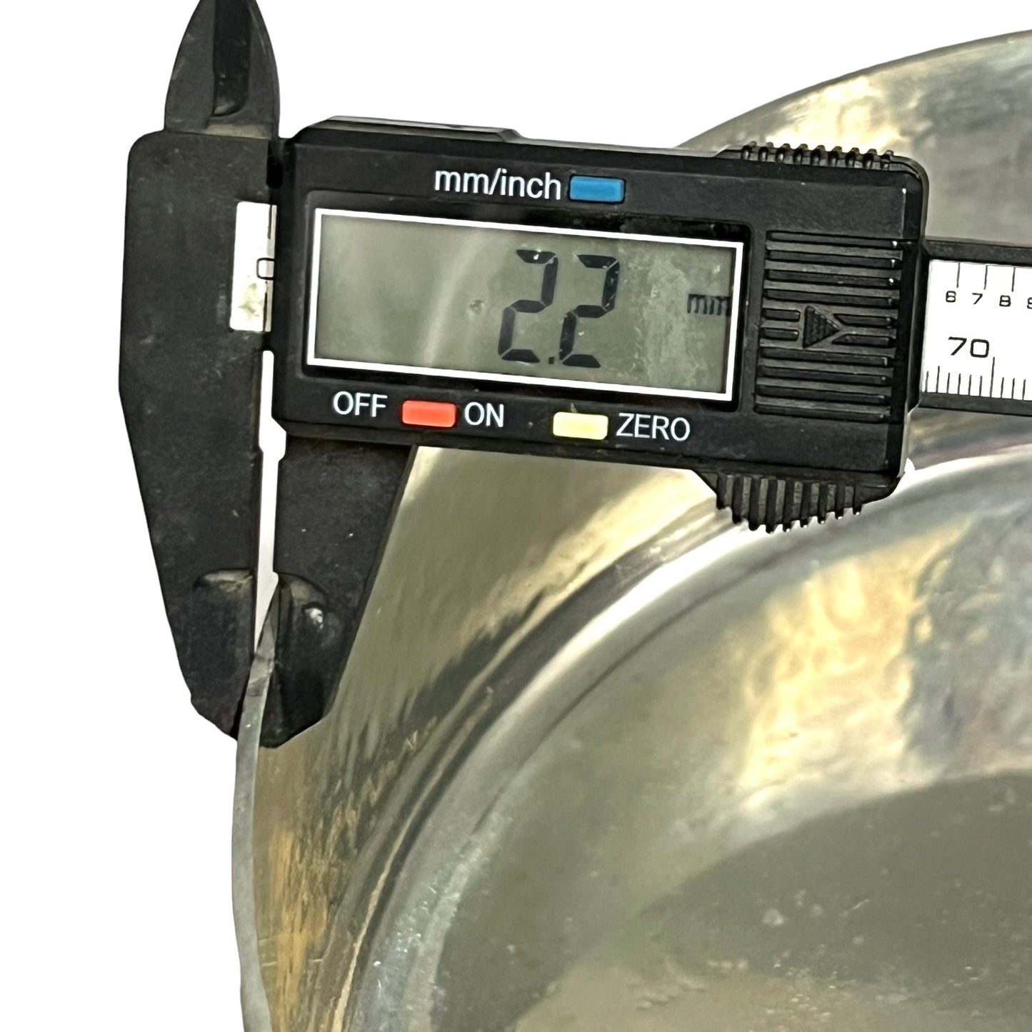 Digital caliper measuring a copper pan with a clear background