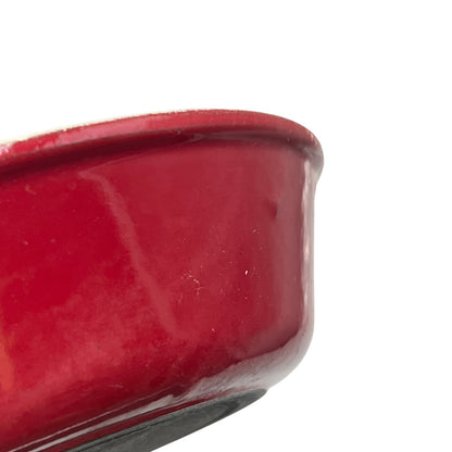 Close-up of a glossy red ceramic dish corner on a plain white background.