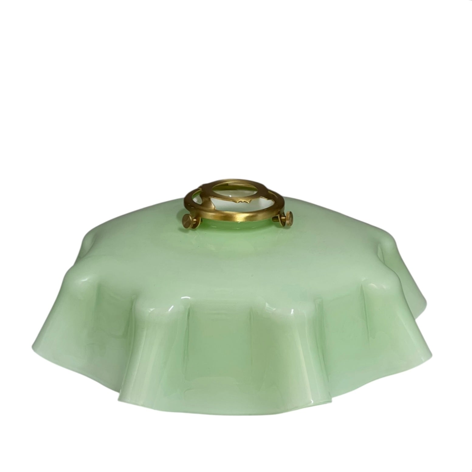 pale green milk glass lampshade with brass fittings on a white background
