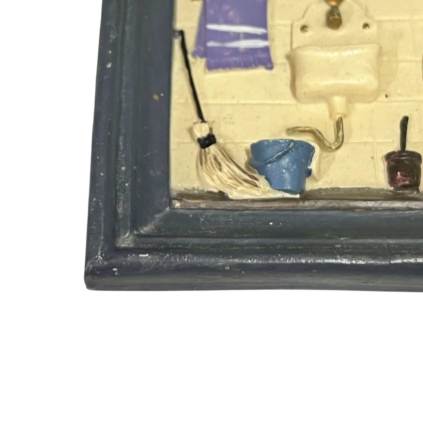 Small model of a bathroom scene with a toilet, sink, and other fixtures inside a framed display.