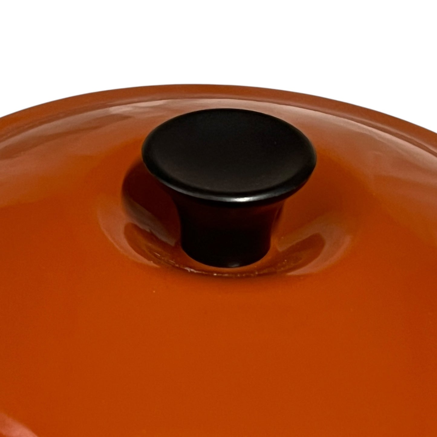 Close up of a rust coloured cast iron saucepan with lid on a white background