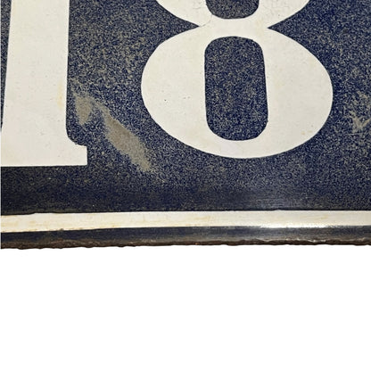 Close up of a blue enamel plaque with a white number 18 on a white background 