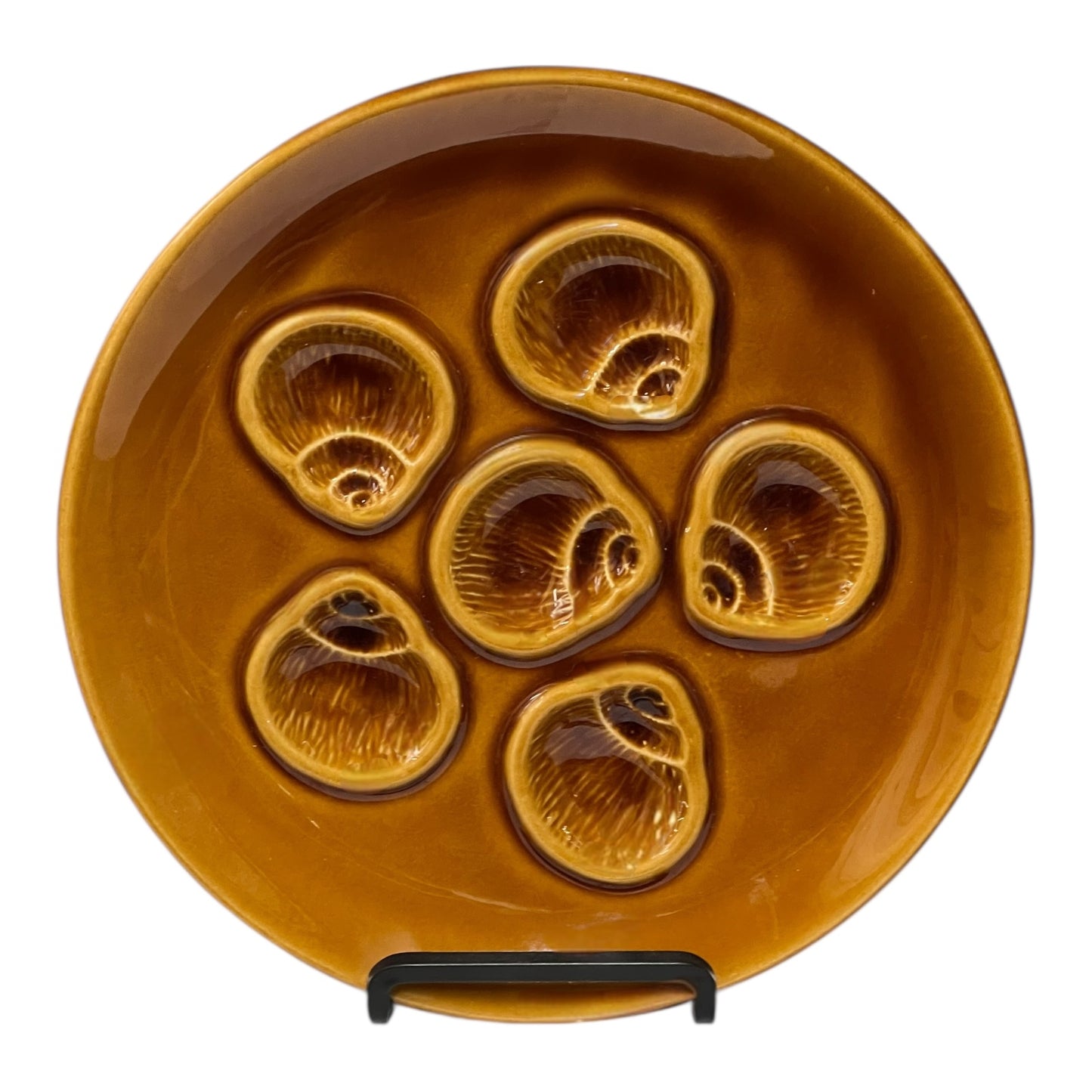 Brown ceramic plate with six shell-shaped compartments on a white background