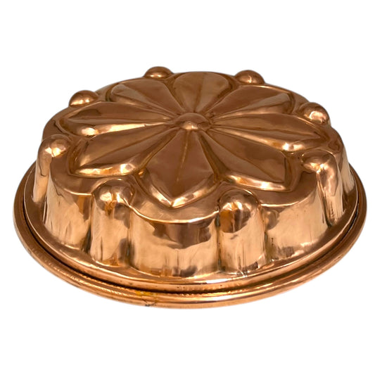 Vintage French round copper cake tin or jelly mold with decorative design on a white background