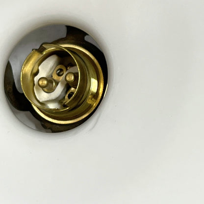 A close-up of a brass light bulb socket or electrical connector recessed into a white surface.