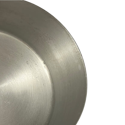 Close-up of a brushed metal pan rim on a plain white background.