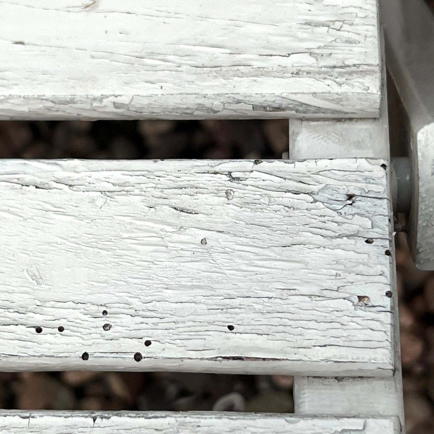 Close-up detail of French wooden slatted chairs, highlighting their condition in an outdoor setting.