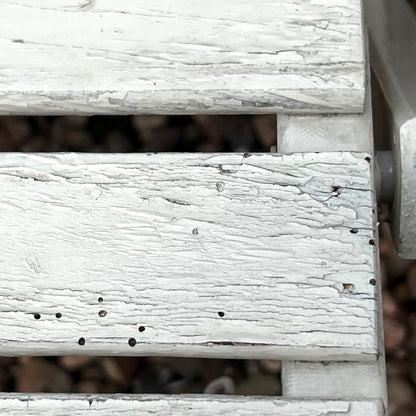 Close-up detail of French wooden slatted chairs, highlighting their condition in an outdoor setting.