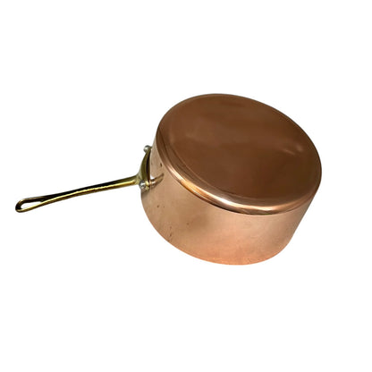 A copper saucepan with a lid and a long brass handle, shown from an elevated angle on a plain white background.