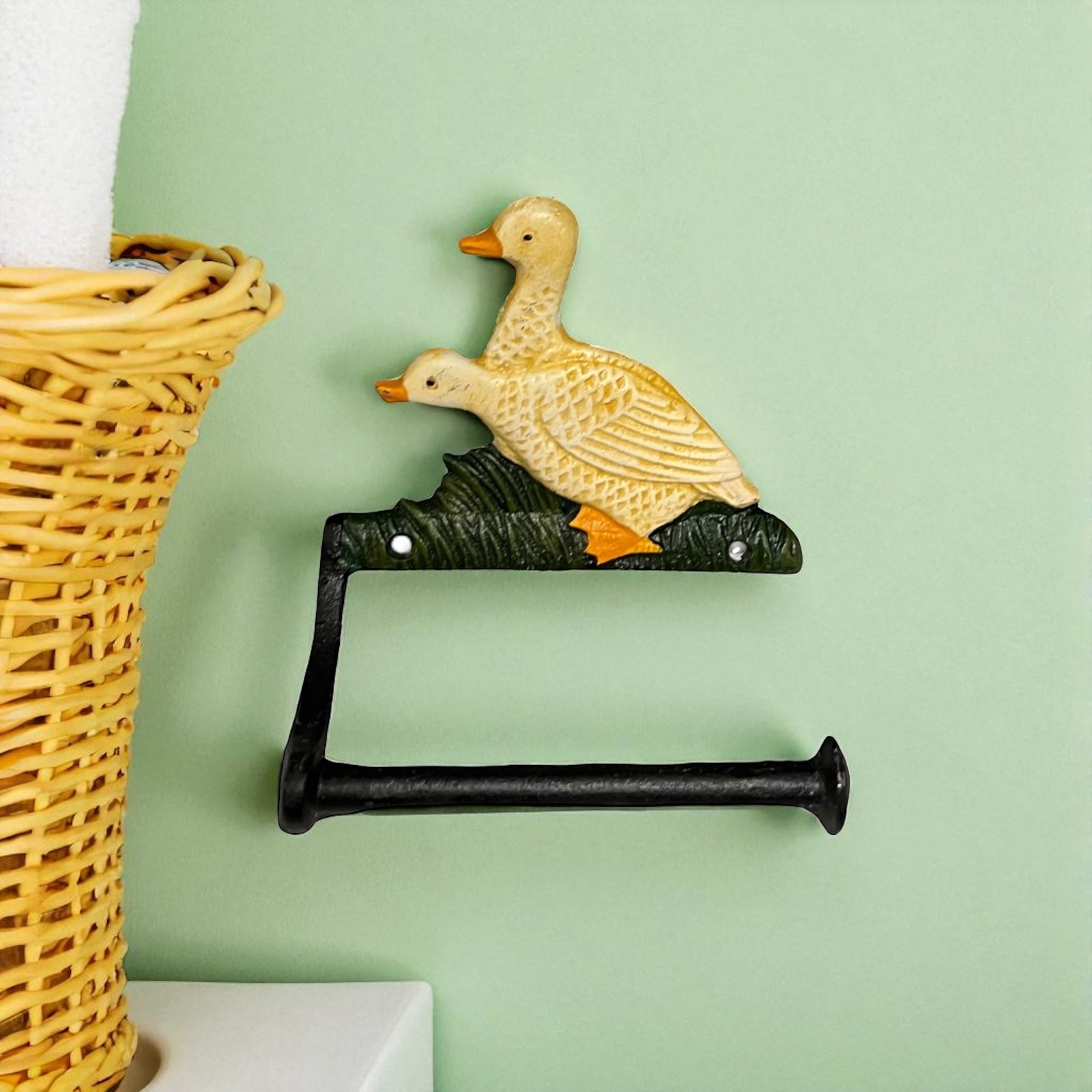 French farmhouse style goose cast iron toilet roll holder on a green wall with a bathroom in the  background