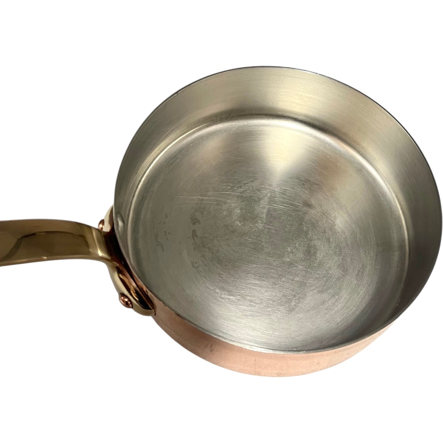 Small copper frying pan with a brass handle and tin lining on a white background