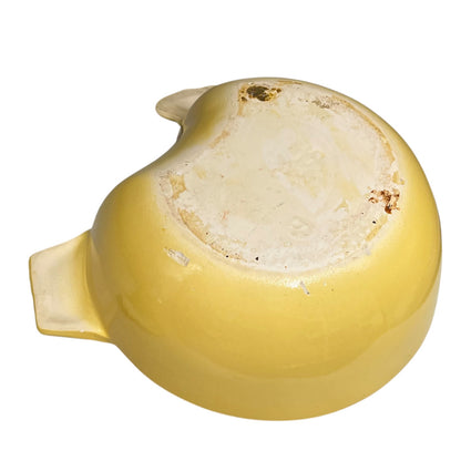 A yellow ceramic bowl viewed from the underside, showing a glossy glazed finish, a light cream-colored base, and a small side tab, isolated on a white background.