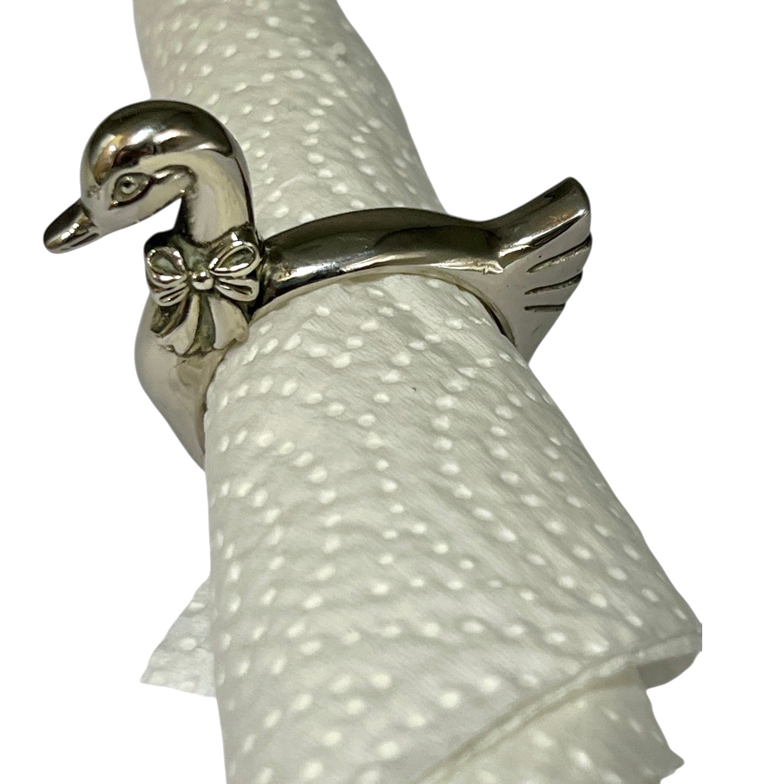 Close-up of a swan shaped silver plated napkin ring with a paper serviette on a white background