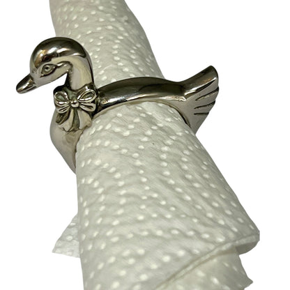 Close-up of a swan shaped silver plated napkin ring with a paper serviette on a white background