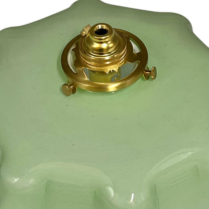 pale green milk glass lampshade with brass fittings on a white background