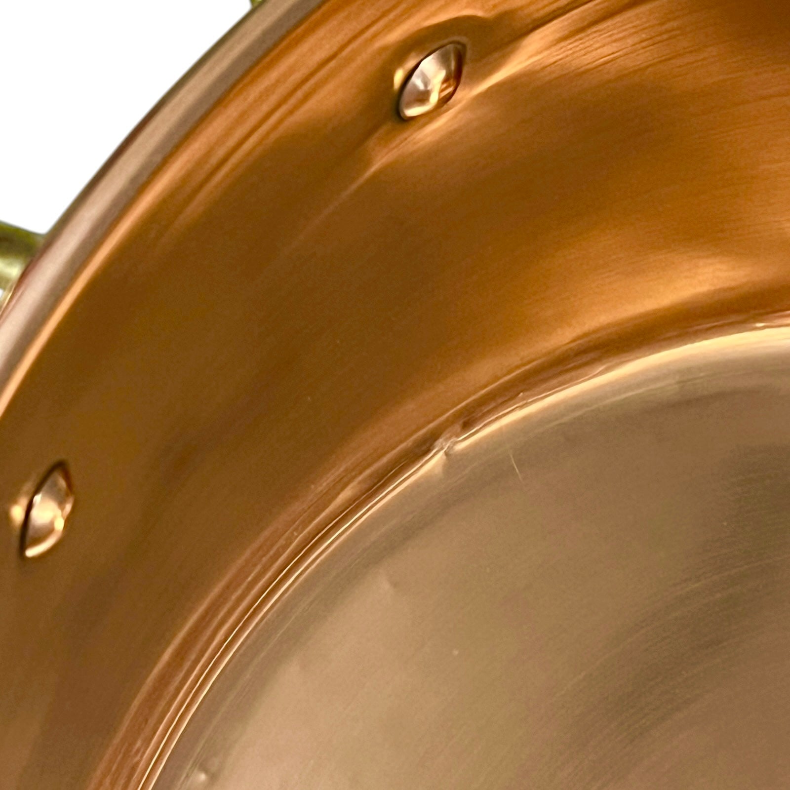 Close-up of a copper up cycled sink with brass handles on a white background.