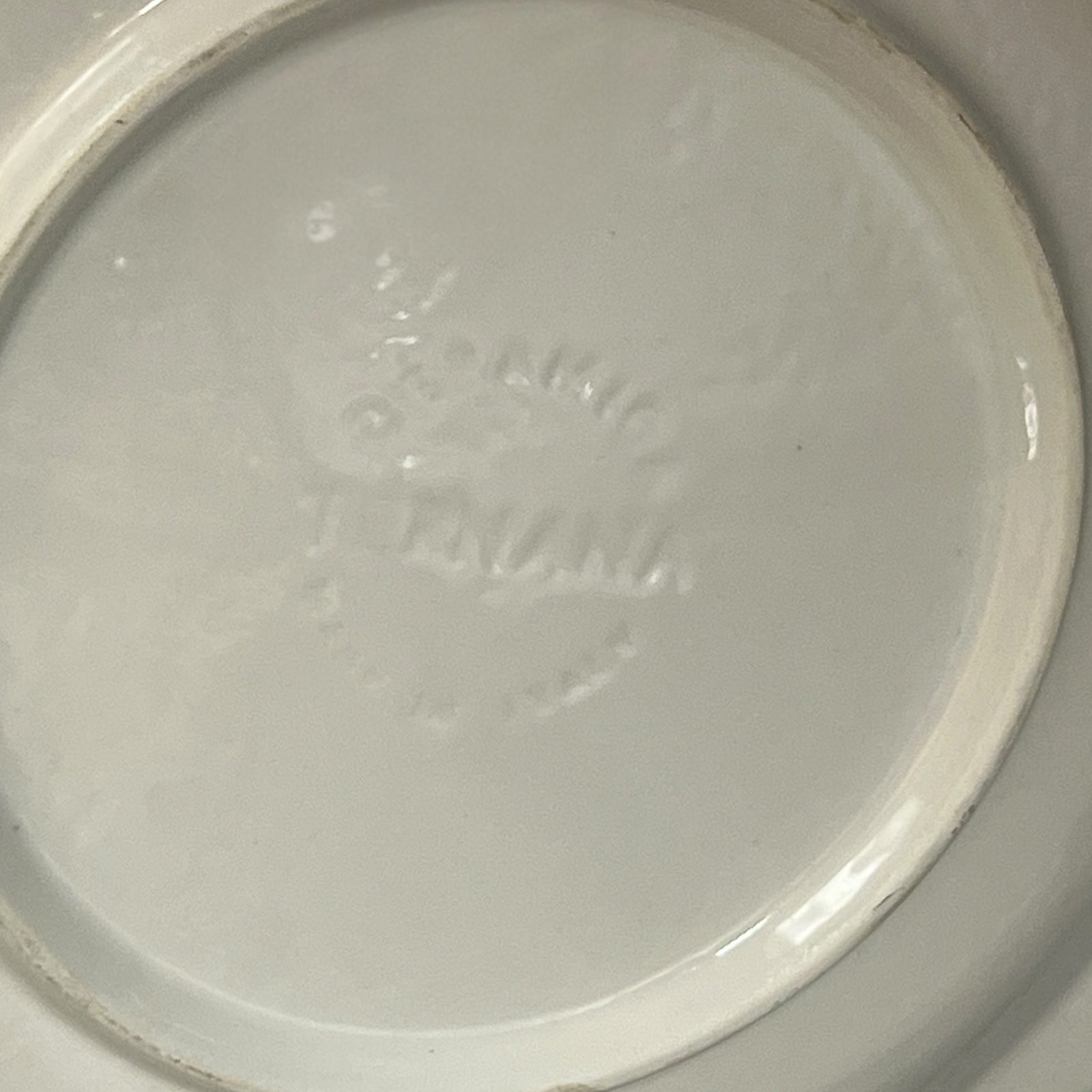 Back of La Raclette plate with a makers stamp on a white background 
