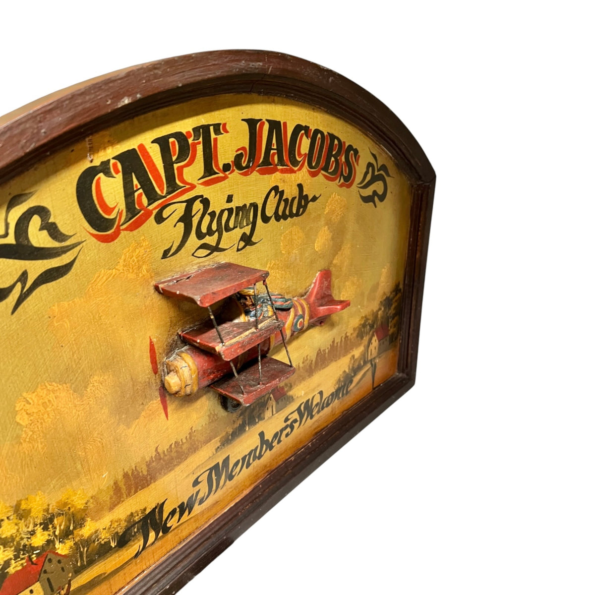 Vintage wooden wall sign for 'Capt. Jacobs Racing Club' featuring a painted red biplane and yellow sky background, photographed against a white studio background.