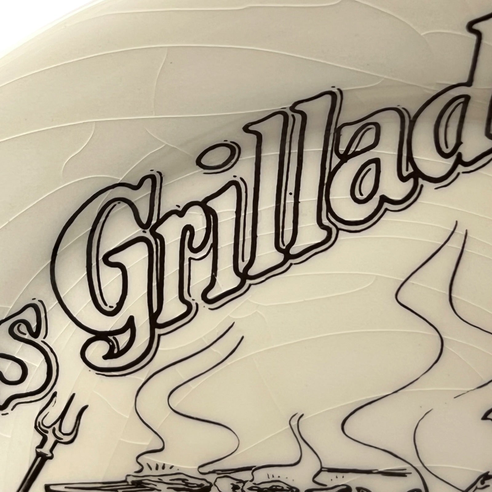 Decorative plate with 'Grillades' text and grill graphics on a beige background