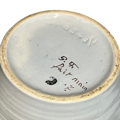 Close-up of the bottom of a ceramic bowl or vase, showing a light gray glazed interior with a natural beige rim, hand-written maker's marks reading 'P. R.