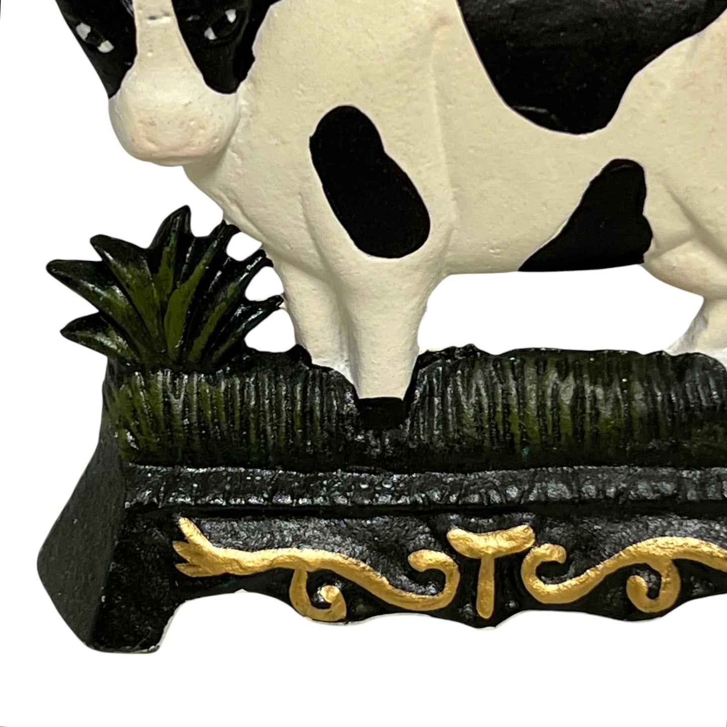 Close up of small cow shaped cast iron doorstop on a white background