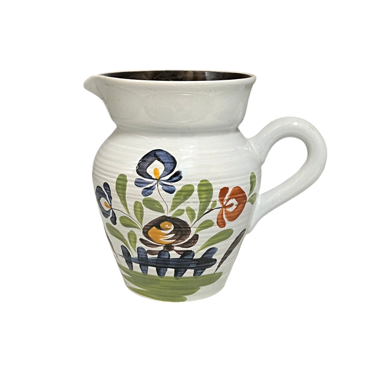 A white ceramic pitcher with a handle and pouring spout, decorated with a hand-painted folk art style design featuring a bird, flowers, and leaves.