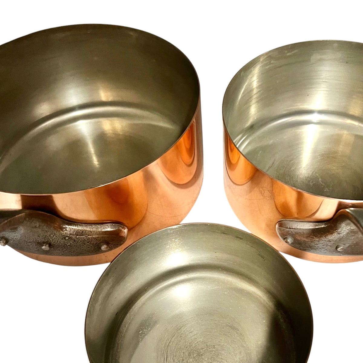 Three copper saucepans with dark metal handles, shown from different angles on a white background.