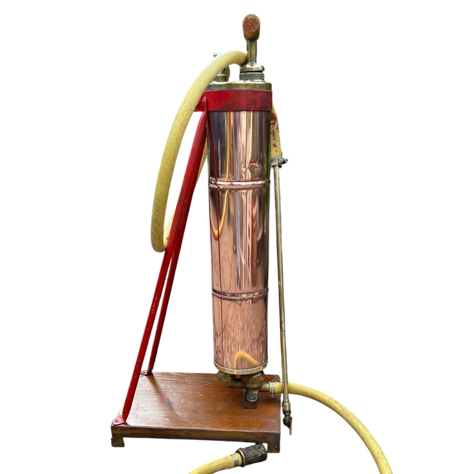 French vintage copper garden sprayer with a yellow hose and nozzle, standing upright on a wooden mount with a red-painted metal bracket. A wooden handle for pumping sits at the top, making it ideal for a vintage garden, all set against a white background.
