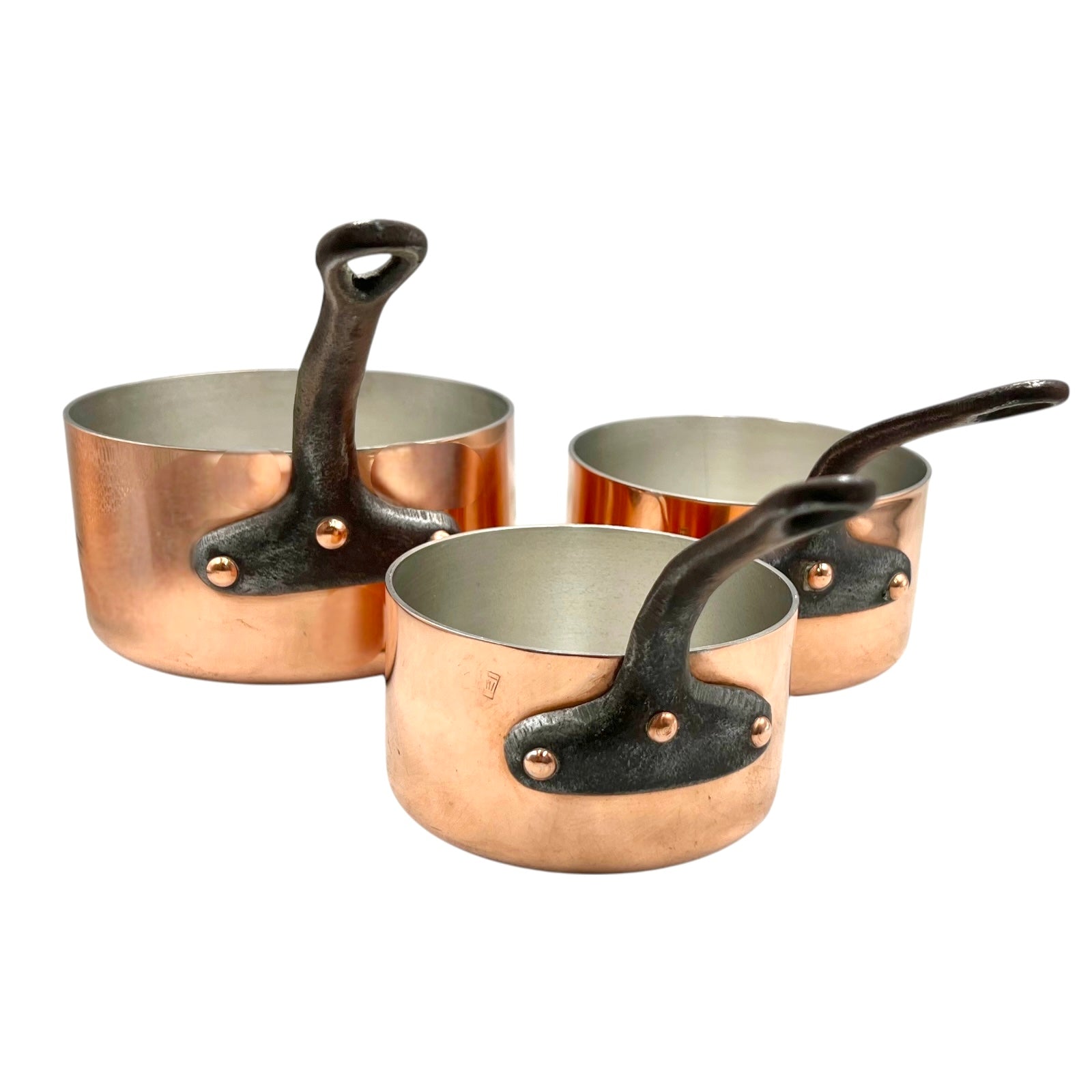 Set of three copper 2mm saucepans with new tin lining and black handles on a white background