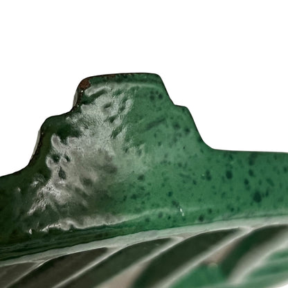 Close up of a green vintage French cast iron enamelled pan trivet on a white background
