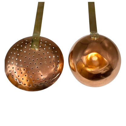 Set of 2 French copper utensils with long brass handles, includes a straining spoon and a ladle on a white background