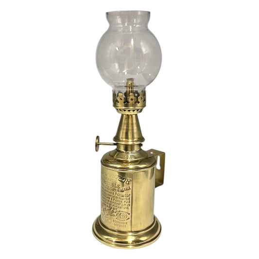 Brass oil lamp with clear glass chimney on a white background