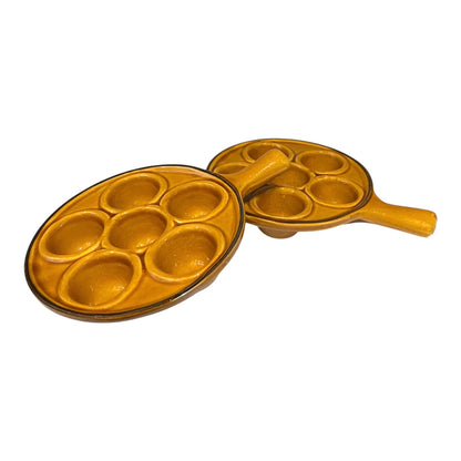 pair of amber-coloured French ceramic escargots plates with handles on a white background