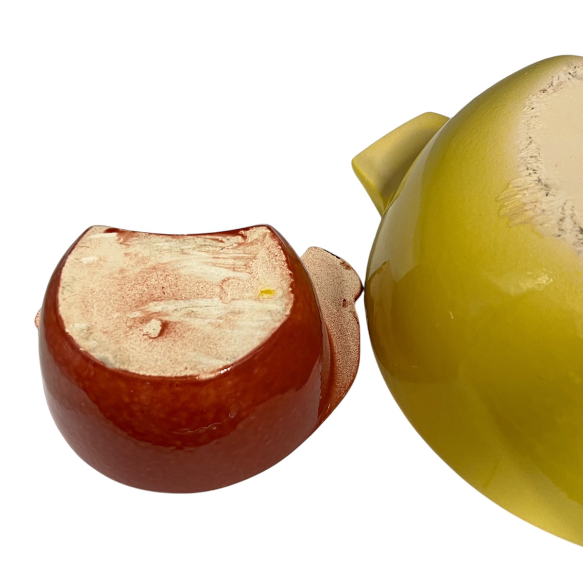 A glossy ceramic bowl set bases shown in a close-up studio shot on a white background, with one side displaying a reddish-brown glazed interior and the other side showing a yellow-green glazed exterior.