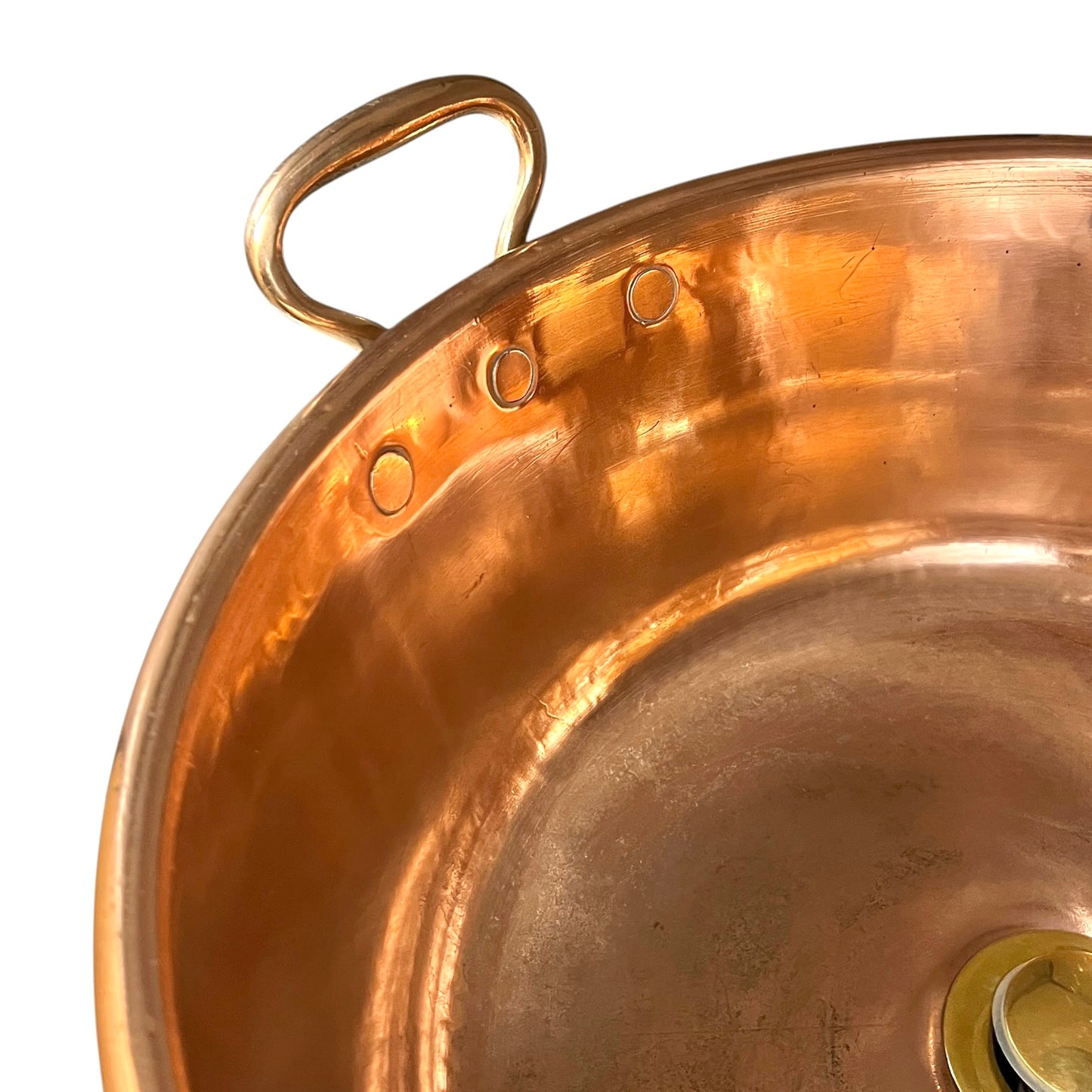 Close-up of a copper sink with a curved handle, showing the polished metallic interior and exterior against a white background.