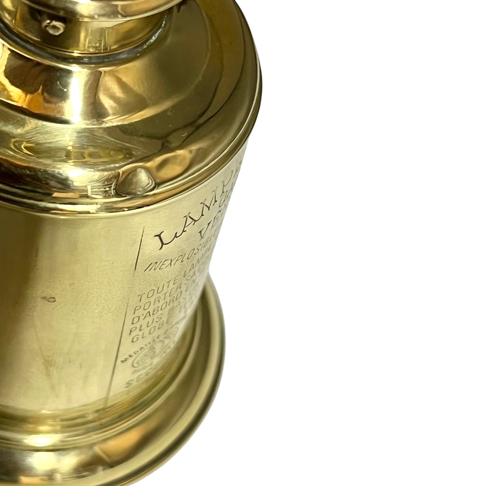 Close-up of a brass lantern with engraved text on a white background
